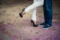 Beautiful legs of young girl in high heels next to the legs Man in pink flower petals, style, fashion, concept, romance Royalty Free Stock Photo