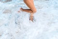 Beautiful legs of a young girl in the ocean foam. The wave rolls on the shore and breaks on the legs. Paradise beach of Royalty Free Stock Photo
