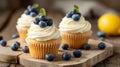 Beautiful lemon vanilla cupcakes with cream cheese frosting decorated with fresh blueberries and green leaves. Close up food