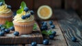 Beautiful lemon vanilla cupcakes with cream cheese frosting decorated with fresh blueberries and green leaves. Close up food Royalty Free Stock Photo