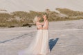 Beautiful lesbian couple walking on sand along river bank on their wedding day