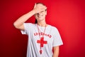 Beautiful lifeguard woman wearing t-shirt with red cross using whistle over isolated background smiling and laughing with hand on