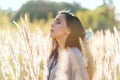 Beautiful lifestyle middle age woman holding meadow spikelets in hand and blowing on it, pollen and dust in air, blurred defocused