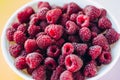 A beautiful light blue bowl of fruit with raspberries, blueberries and blackberries on yellow background, top view, studio shot Royalty Free Stock Photo