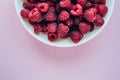 Closeup white plate with raspberries on a colored background, top view