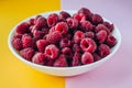 Closeup white plate with raspberries on a colored background