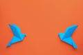 Beautiful light blue origami birds on orange background, flat lay. Space for text Royalty Free Stock Photo