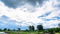 Beautiful light in dark and dramatic storm clouds after rain. Field of green plant and pond over dramatic blue sky. Royalty Free Stock Photo