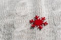 Beautiful light gray knitted pattern with red paper snowflake , knitted scarf close up. Knitted background. Royalty Free Stock Photo