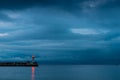 Beautiful lighthouse on the seashore at dusk, rainy clouds over