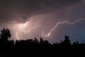 beautiful lightning during a thunderstorm at night in a forest that caused a fire, against a dark sky with rain Royalty Free Stock Photo