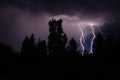 beautiful lightning during a thunderstorm at night in a forest that caused a fire, against a dark sky with rain Royalty Free Stock Photo
