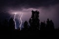 beautiful lightning during a thunderstorm at night in a forest that caused a fire, against a dark sky with rain Royalty Free Stock Photo