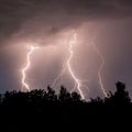 beautiful lightning during a thunderstorm at night in a forest that caused a fire, against a dark sky with rain Royalty Free Stock Photo