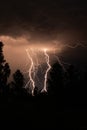 beautiful lightning during a thunderstorm at night in a forest that caused a fire, against a dark sky with rain Royalty Free Stock Photo