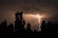 beautiful lightning during a thunderstorm at night in a forest that caused a fire, against a dark sky with rain Royalty Free Stock Photo