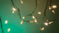 Beautiful lights on wire against green brown background. Defocused glowing lights on LED Garland in dark room close-up Royalty Free Stock Photo