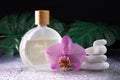 Beautiful lilac orchid flower and transparent bottle of perfume with white stones and monstera leaves on wet background Royalty Free Stock Photo