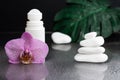 Beautiful lilac orchid flower and white roll-on deodorant with white stones and monstera leaves on black wet background Royalty Free Stock Photo