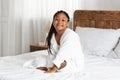 Beautiful little african american girl in bathrobe relaxing on bed after shower Royalty Free Stock Photo