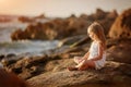 Beautiful little angel gir sitting on a rock and looking into the distance Royalty Free Stock Photo