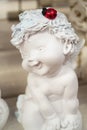 Beautiful little angel statue. Detail and portrait of sitting cupid with ladybug Royalty Free Stock Photo