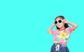 Beautiful little Asian kid girl wearing a flowers summer dress and sunglasses isolated on cyan background with copy space Royalty Free Stock Photo