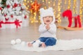 Beautiful little baby boy celebrates Christmas. New Year`s holidays. Baby in a Christmas costume casual clothes with gifts on fur Royalty Free Stock Photo