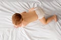 Beautiful little baby boy in diaper lying on bed, crawling, playing  over white studio background Royalty Free Stock Photo