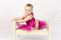 Beautiful little baby girl sitting on the bed wearing pink dress Royalty Free Stock Photo