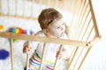 Beautiful little baby girl standing inside playpen. Cute adorable child playing with colorful toy Royalty Free Stock Photo