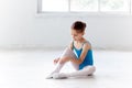 Beautiful little ballerina in blue dress for dancing puting on foot pointe shoes Royalty Free Stock Photo