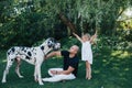 Beautiful little blonde baby girl has happy fun smiling face playing in a white dress with her dad and a dog, Child