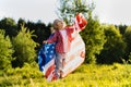 beautiful little blonde girl with the American flag in nature in the sunlight Royalty Free Stock Photo