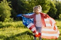 beautiful little blonde girl with the American flag in nature in the sunlight Royalty Free Stock Photo