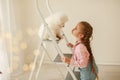 Beautiful little blonde hair girl, has fun smile face, embraces and plays with puppy dog Japanese Spitz. Child and Royalty Free Stock Photo