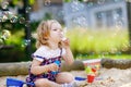 Beautiful little blonde toddler girl having fun with blowing soap bubble blower. Cute adorable baby child playing on Royalty Free Stock Photo