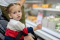 Beautiful little caucasian girl chooses products in the supermarket. Closeup portrait of a young buyer