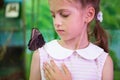 Beautiful little caucasian girl in dress with big black insect butterfly