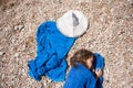 Beautiful little girl lying on beach wrapped in blue towel near white hat Royalty Free Stock Photo