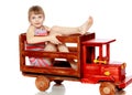 The girl is sitting on a large toy wooden car. Royalty Free Stock Photo