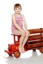 The girl is sitting on a large toy wooden car. Royalty Free Stock Photo