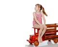 The girl is sitting on a large toy wooden car. Royalty Free Stock Photo