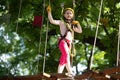 Beautiful little child climbing and having fun in adventure Park. Cargo net climbing and hanging log. Carefree childhood Royalty Free Stock Photo