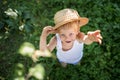 Beautiful little child with straw hat looking up and hand waving