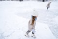 Beautiful little cute girl learn to skate on ice skating rink in park. Fall down and have fun. Stylish look, warm woolen coat, Royalty Free Stock Photo