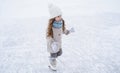 Beautiful little cute girl learn to skate on ice skating rink in park. Fall down and have fun. Stylish look, warm woolen coat, Royalty Free Stock Photo