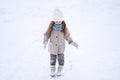 Beautiful little cute girl learn to skate on ice skating rink in park. Fall down and have fun. Stylish look, warm woolen coat, Royalty Free Stock Photo