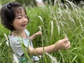 Beautiful little cute girl is picking up flower in the grass field with copy space Royalty Free Stock Photo