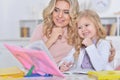 Beautiful little cute girl reading book with mother at the table at home Royalty Free Stock Photo